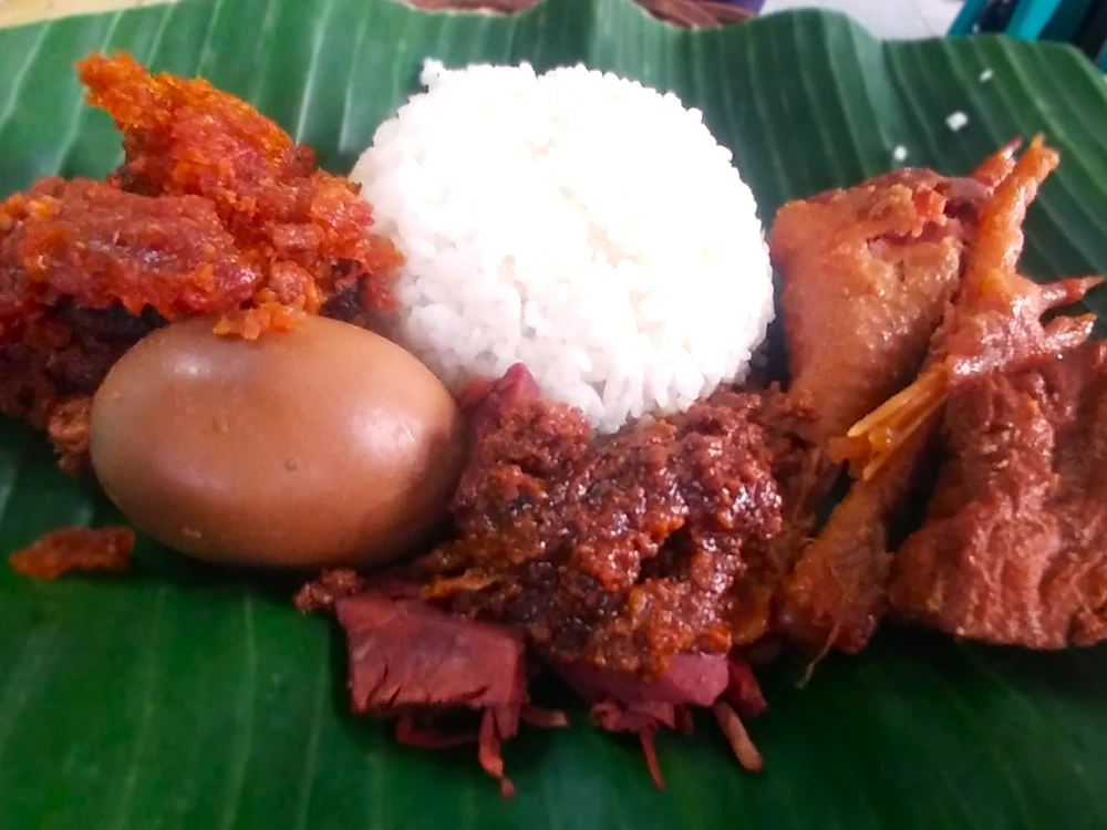 Nasi dengan lauk ayam dan telur di atas daun pisang